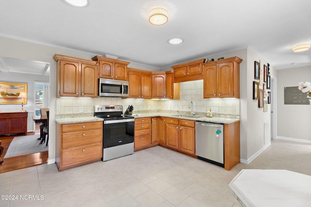 kitchen featuring decorative backsplash, sink, light tile patterned flooring, crown molding, and appliances with stainless steel finishes