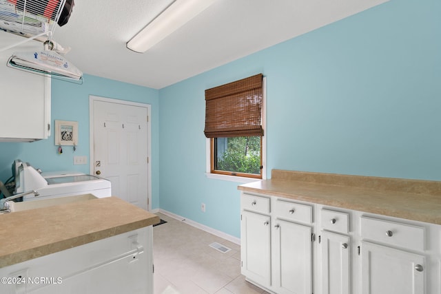 laundry area featuring light tile patterned flooring, washer / clothes dryer, and cabinets