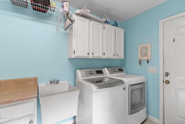 laundry area with a textured ceiling, washing machine and clothes dryer, sink, and cabinets