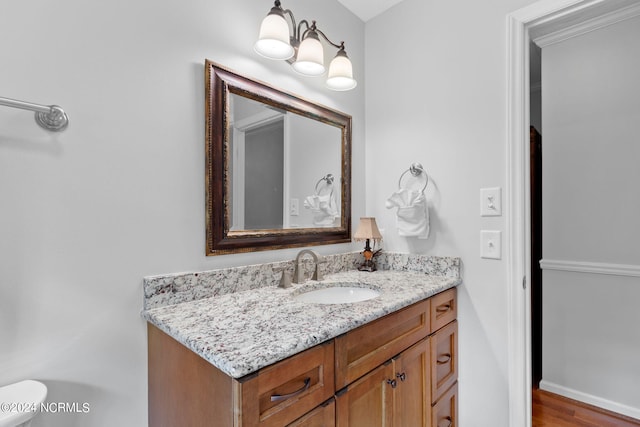 bathroom featuring wood-type flooring, vanity, and toilet