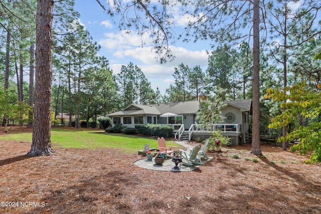 rear view of house with a patio, a fire pit, a wooden deck, and a lawn