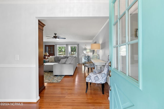 living room featuring wood-type flooring, ornamental molding, and ceiling fan