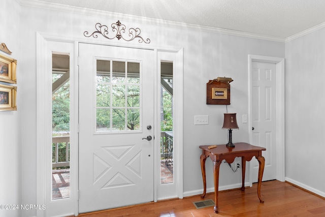 entryway with hardwood / wood-style flooring, crown molding, and a textured ceiling