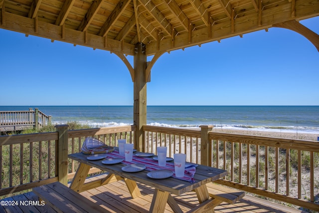 wooden terrace featuring a water view and a view of the beach