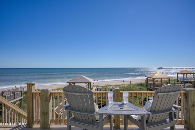 wooden terrace with a view of the beach, a water view, and a gazebo