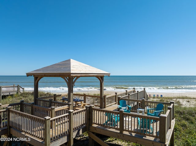 view of property's community featuring a gazebo, a deck with water view, and a view of the beach