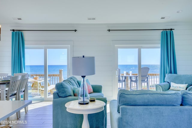 living room with a water view, wooden walls, and wood-type flooring