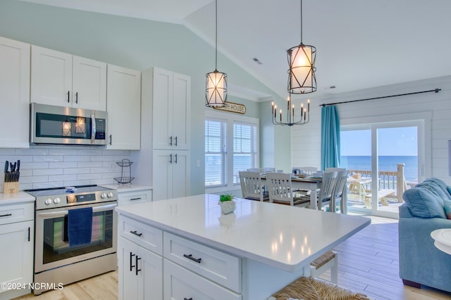 kitchen with appliances with stainless steel finishes, a water view, a healthy amount of sunlight, and lofted ceiling