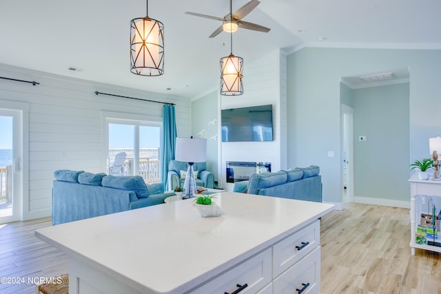 kitchen with vaulted ceiling, decorative light fixtures, light hardwood / wood-style flooring, and white cabinets