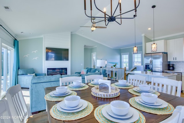1016 New River Inlet Rd, North Topsail Beach, NC 28460 - dining room featuring visible vents, an inviting chandelier, crown molding, vaulted ceiling, and a large fireplace