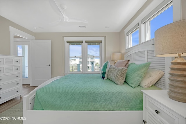 bedroom with ceiling fan, multiple windows, and light wood-type flooring