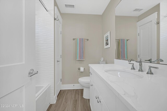 full bathroom featuring toilet, hardwood / wood-style floors, vanity, and bathing tub / shower combination