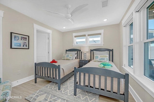 bedroom featuring ceiling fan, multiple windows, and light hardwood / wood-style floors