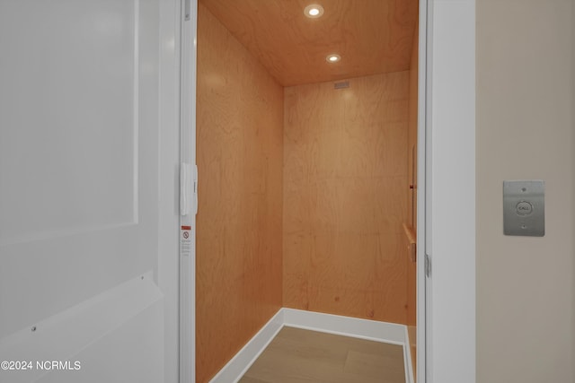 interior details featuring wood walls, hardwood / wood-style flooring, and elevator