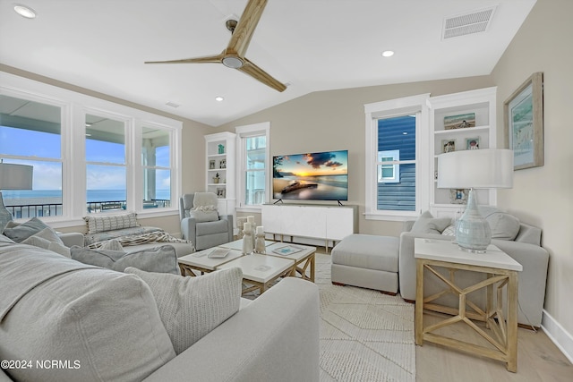 living room with light hardwood / wood-style flooring, a water view, and vaulted ceiling