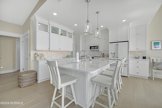 kitchen featuring white cabinetry, hanging light fixtures, light wood-type flooring, and tasteful backsplash