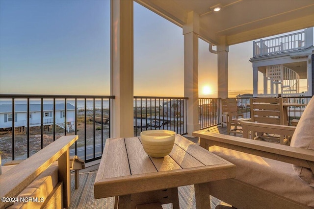 balcony at dusk featuring a water view