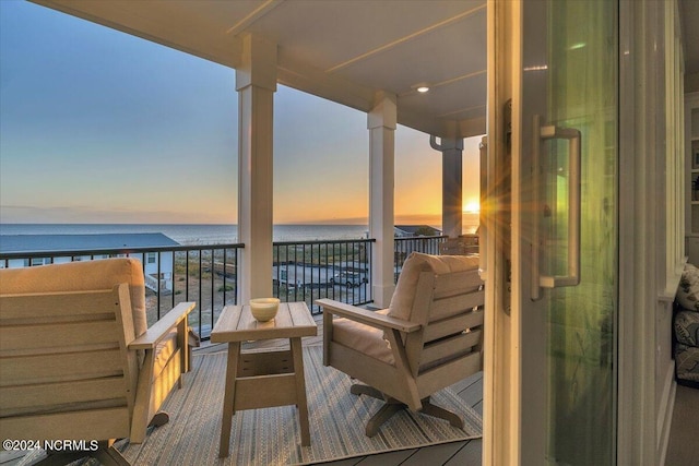 balcony at dusk featuring a water view