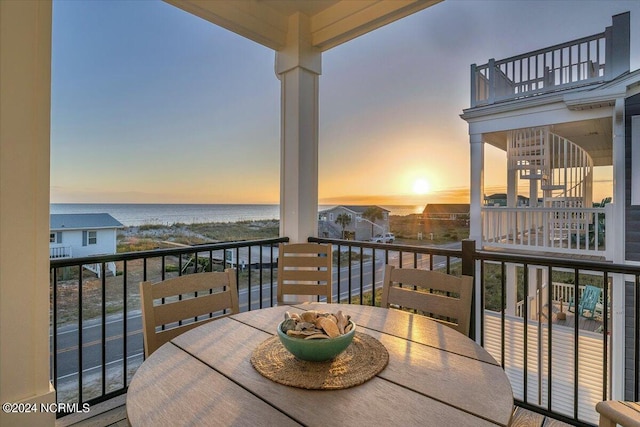 balcony at dusk featuring a water view