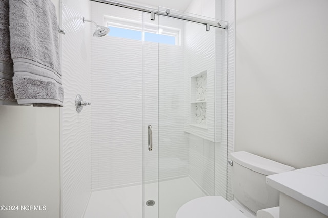 bathroom featuring toilet, a shower with shower door, and vanity