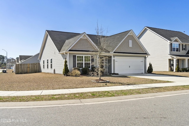 view of front facade with driveway, an attached garage, and fence