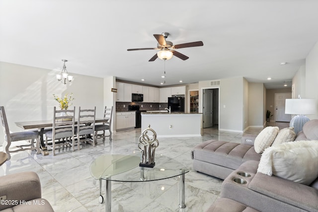 living area with baseboards, visible vents, marble finish floor, ceiling fan with notable chandelier, and recessed lighting