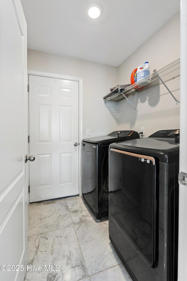 laundry area with laundry area, washing machine and dryer, and marble finish floor