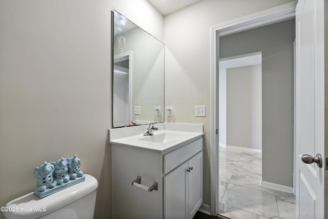 bathroom featuring toilet, marble finish floor, baseboards, and vanity