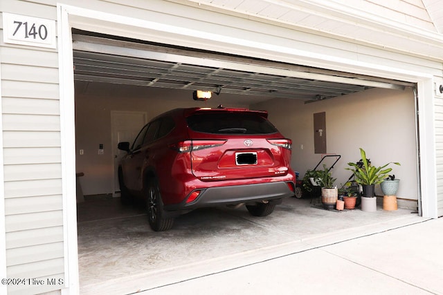 garage featuring a garage door opener, electric panel, and a carport