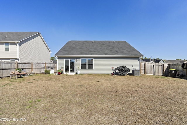 rear view of house with a fenced backyard, a lawn, and central AC