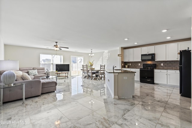 kitchen featuring white cabinetry, open floor plan, marble finish floor, black appliances, and a center island with sink