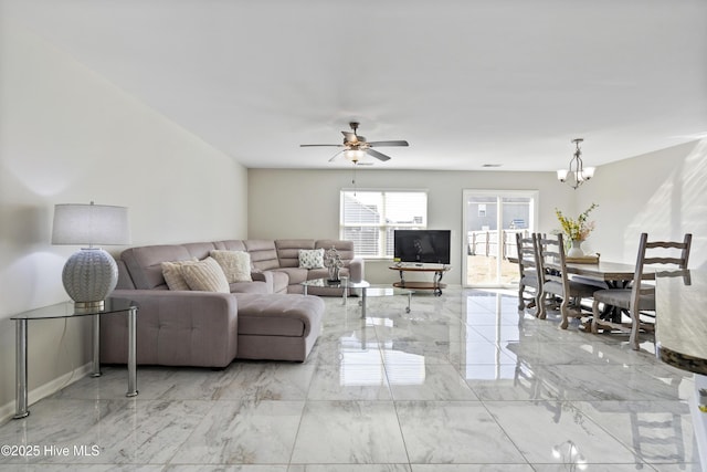 living room with marble finish floor, baseboards, and ceiling fan with notable chandelier