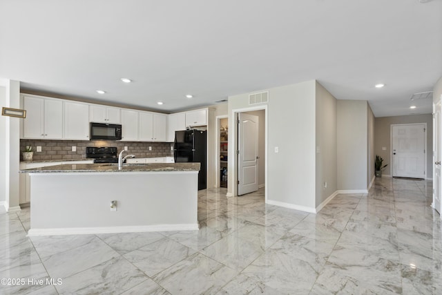 kitchen featuring a center island with sink, visible vents, white cabinets, light stone counters, and black appliances