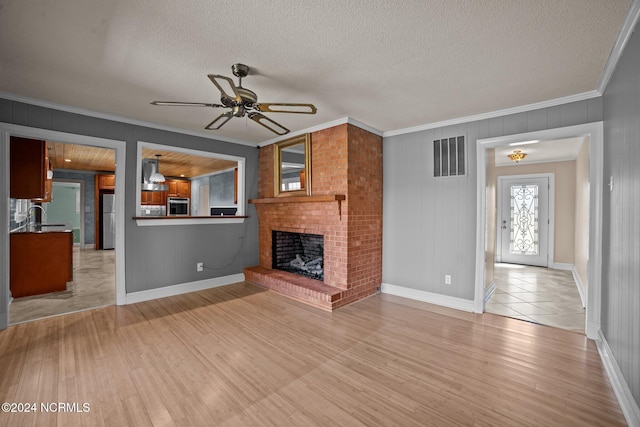 unfurnished living room featuring light hardwood / wood-style flooring, ceiling fan, a fireplace, and crown molding