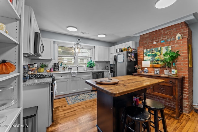 kitchen with white cabinetry, appliances with stainless steel finishes, light hardwood / wood-style floors, and a kitchen breakfast bar