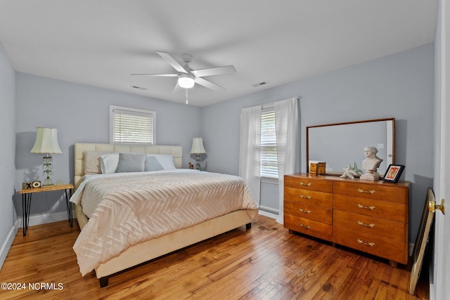 bedroom featuring hardwood / wood-style floors, multiple windows, and ceiling fan