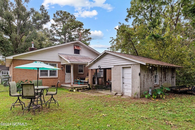 back of house with an outbuilding, a patio area, and a lawn