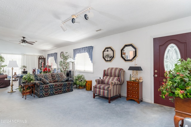 carpeted living room with track lighting, ceiling fan, vaulted ceiling, and a textured ceiling