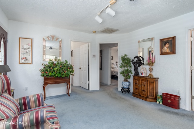 living area featuring light carpet, a textured ceiling, track lighting, and ceiling fan