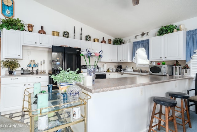 kitchen featuring white cabinets, lofted ceiling, sink, white appliances, and a breakfast bar area