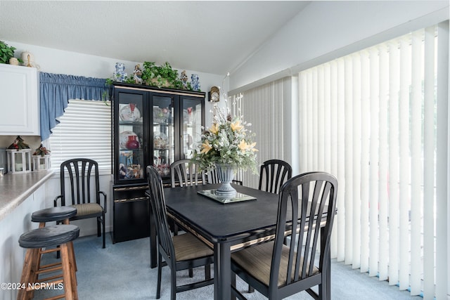 dining space featuring vaulted ceiling and light carpet