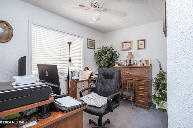 carpeted home office with ceiling fan and a textured ceiling