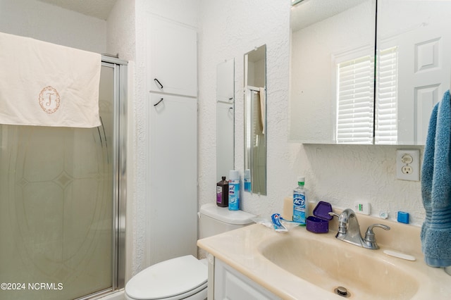 bathroom with vanity, toilet, and a shower with door