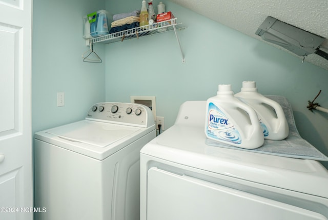 laundry room with a textured ceiling and separate washer and dryer