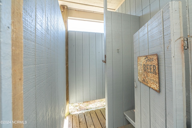 bathroom with wooden walls and wood-type flooring