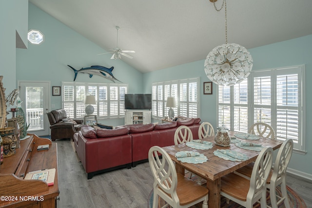 dining space featuring light hardwood / wood-style floors, high vaulted ceiling, and ceiling fan with notable chandelier