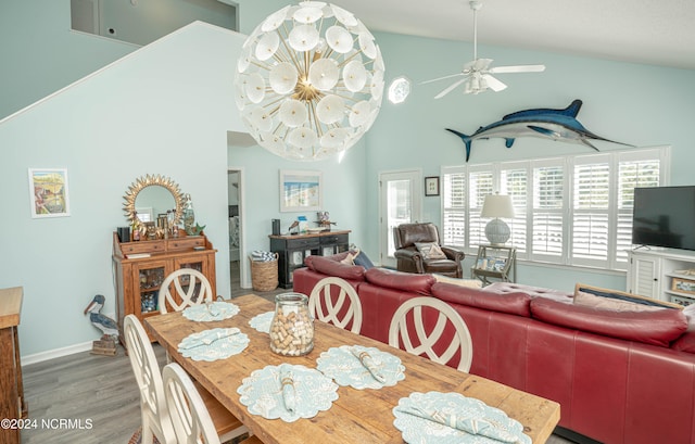 dining area featuring hardwood / wood-style flooring, high vaulted ceiling, and ceiling fan with notable chandelier