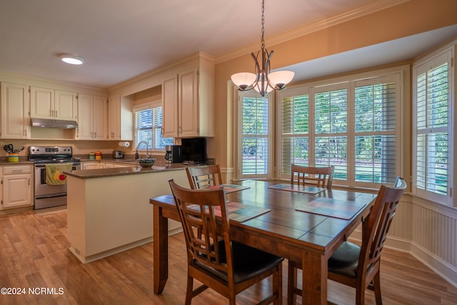 dining space featuring ornamental molding, an inviting chandelier, sink, and light hardwood / wood-style floors