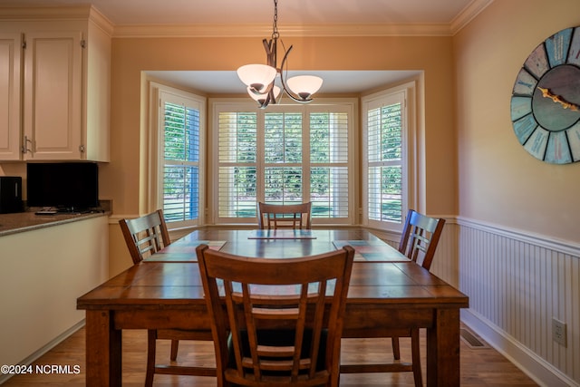 dining area with wood-type flooring, a notable chandelier, and ornamental molding