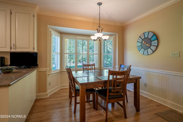 dining space featuring ornamental molding, an inviting chandelier, and light hardwood / wood-style floors